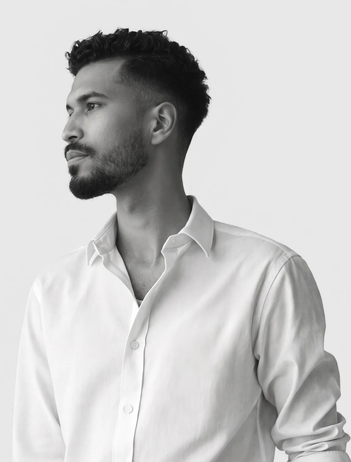 Miguel de los Santos de perfil, de camisa blanca, sobre fondo gris.